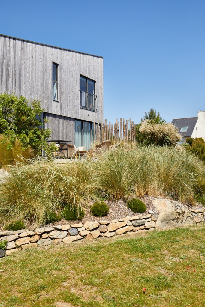massif de graminées devant maison moderne avec muret en pierre naturelle