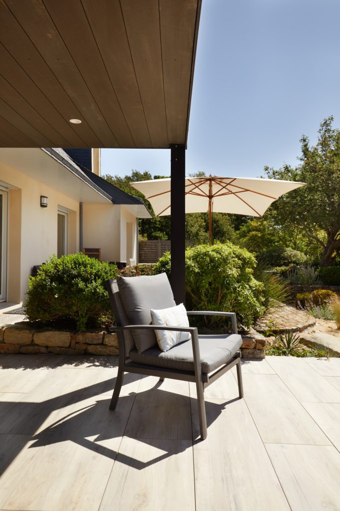 fauteuil sous une pergola sur une terrasse en grès ceram