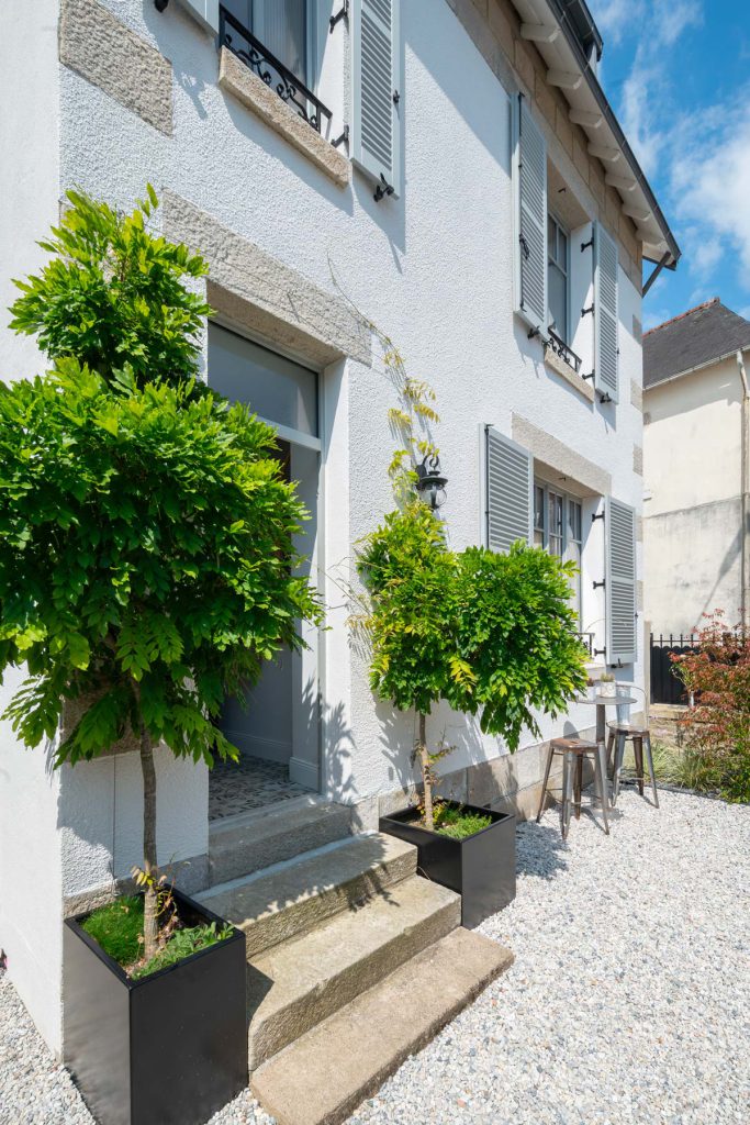 entrée de maison avec deux glycines qui montent en arche