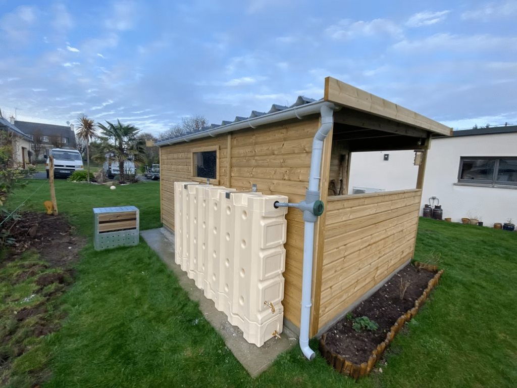 Abri en bois avec un bac de récupération d'eau relié à une goutière