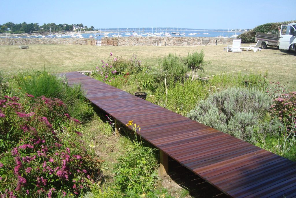 ponton en bois menant à un jardin vue mer